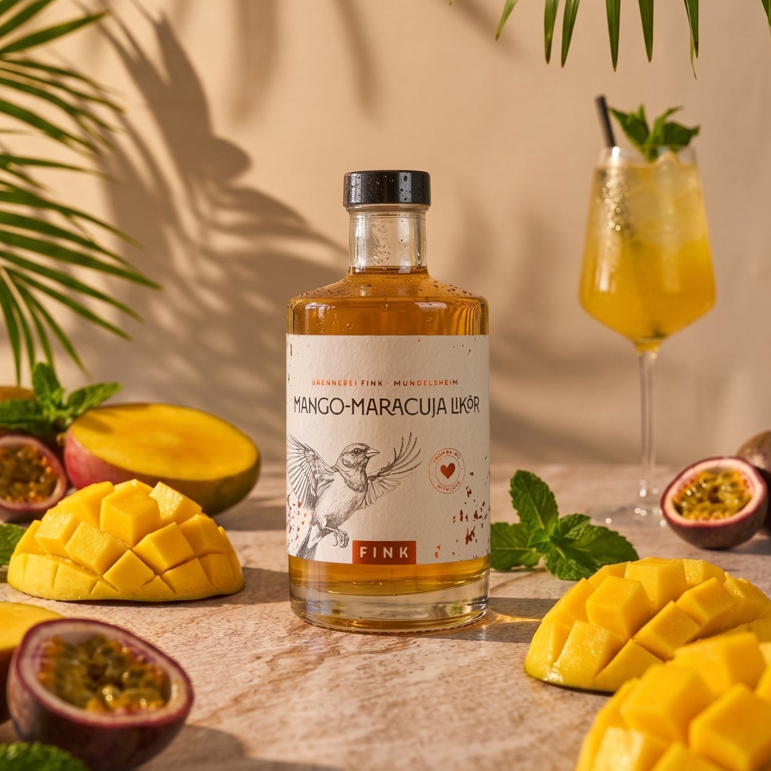 Flasche Mango-Maracuja Likör der Brennerei Fink aus Mundelsheim. Das sommerliche Produktbild zeigt den fruchtigen Likör dekoriert mit aufgeschnittener, frischer Mango, Maracuja und Minze im tropischen Palmenschatten.